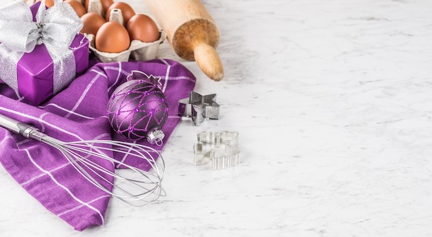 Natale cottura regali viola decorazioni uova e utensili da cucina sul tavolo di marmo.