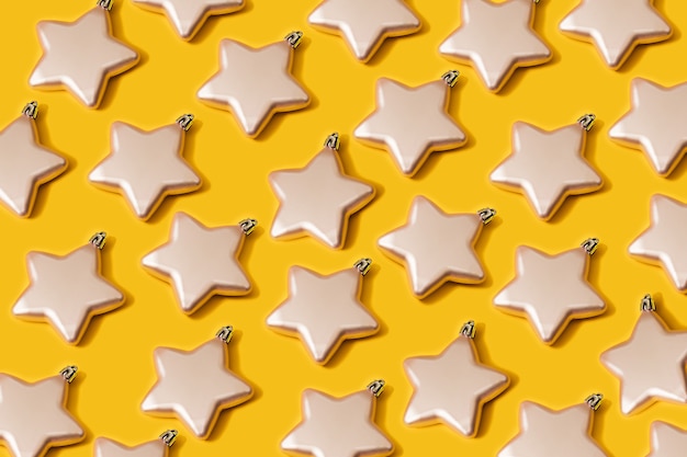 Natale creativo colore vibrante a forma di stella baubles decorazione pattern su carta gialla sullo sfondo. Concetto di posa piatta minimo del nuovo anno con spazio di copia.