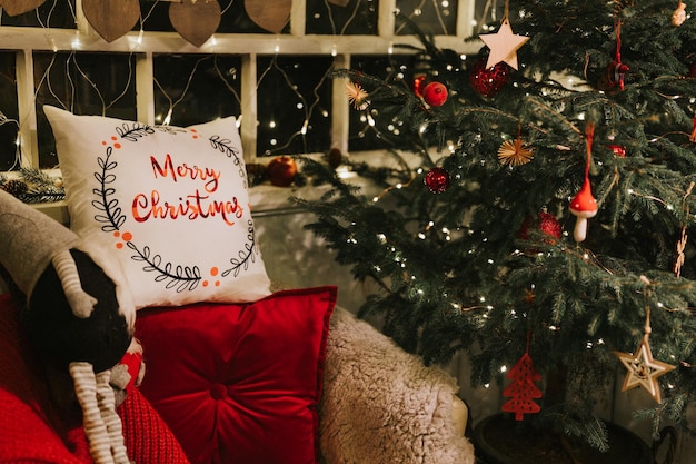 Natale e Capodanno accogliente poltrona morbida o poltrona con un comodo plaid e un cuscino rosso pad e uno gnomo nisse vicino a un albero di Natale decorato stagione delle vacanze invernali a casa