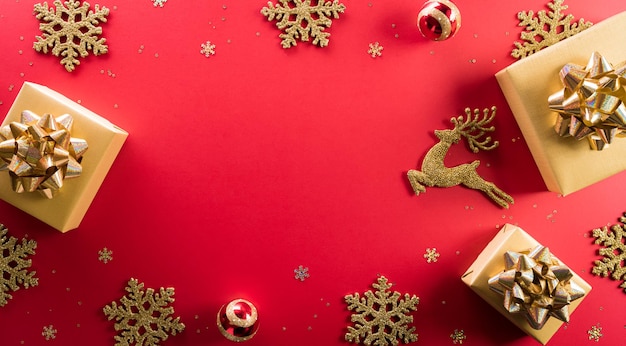 Natale e Capodanno concetto di sfondo. Vista dall'alto di scatola regalo di Natale, renne, palla di Natale e fiocco di neve su sfondo rosso.