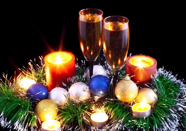 Natale e Capodanno decorazione-palle, orpelli, candele e bicchieri di champagne. Su sfondo nero.