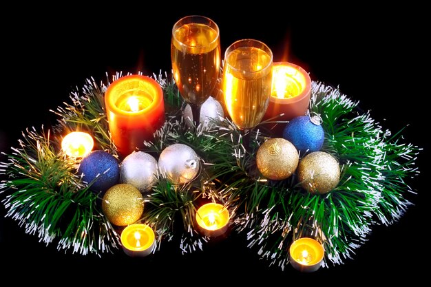 Natale e Capodanno decorazione-palle, orpelli, candele e bicchieri di champagne. Su sfondo nero.