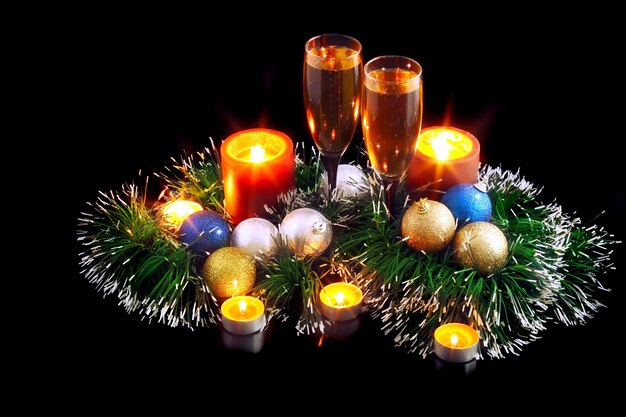 Natale e Capodanno decorazione-palle, orpelli, candele e bicchieri di champagne. Su sfondo nero.