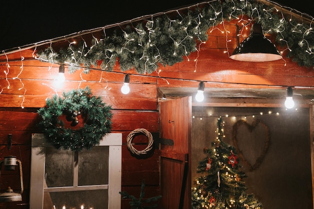 Natale e Capodanno decorazioni natalizie dell'esterno di una casa rurale in legno e tetto rustico paese retrò scena nel sobborgo villaggio vacanze invernali stagione nel sobborgo di campagna