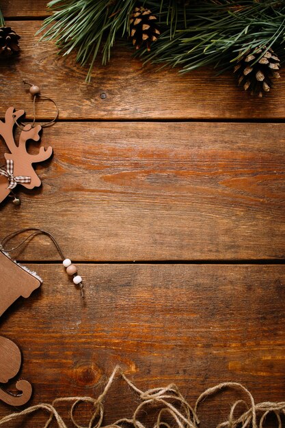 Natale e Capodanno vacanze sfondo Primo piano ornamenti fatti a mano di skate e cervi a sinistra e pino con strobila sopra sul tavolo di legno concetto di decorazione festiva Spazio libero nel mezzo