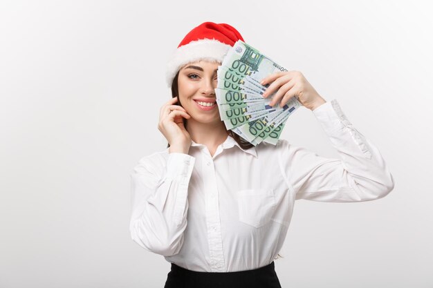 Natale e concetto di finanza Giovane donna d'affari che mostra denaro chiudendo il viso con espressione sorpresa