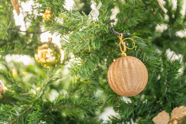 Natale e concetto di stagione delle vacanze. Primo piano dell'ornamento dorato hanking sull'albero di Natale.