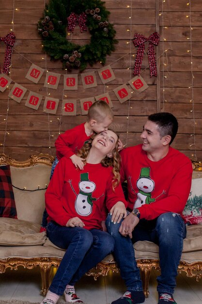 Natale Famiglia Felicità Ritratto di papà mamma e figli seduti su un divano a casa vicino all'albero di Natale tutti sorridono Il concetto di vacanza invernale in famiglia