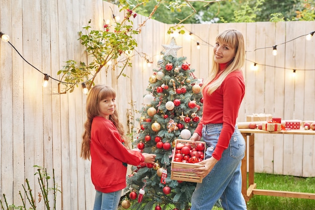 Natale in famiglia a luglio Ritratto di ragazza vicino all'albero di Natale con regali Decorare il pino Winter