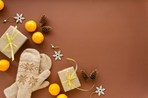 Natale laici piatta. Muffole, confezione regalo, mandarini e decorazioni su fondo marrone, spazio per il testo.