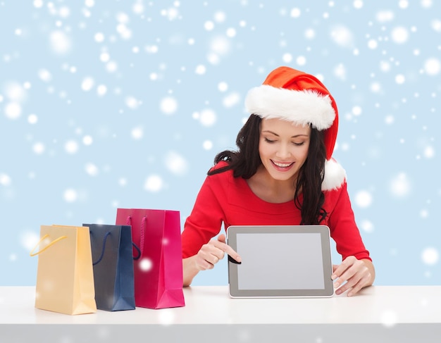 natale, natale, elettronica, gadget concept - donna sorridente con cappello da Babbo Natale con schermo vuoto tablet pc