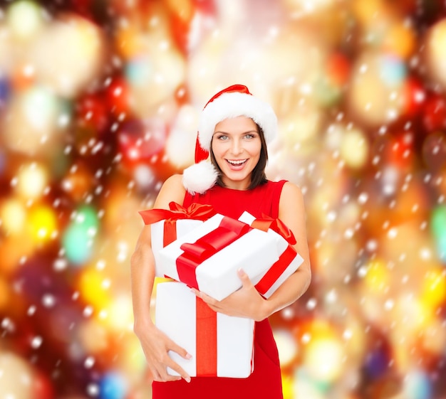 natale, natale, inverno, concetto di felicità - donna sorridente con cappello da Babbo Natale con molte scatole regalo