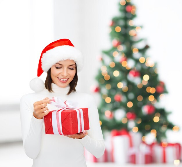 natale, natale, inverno, concetto di felicità - donna sorridente con cappello da Babbo Natale con scatola regalo