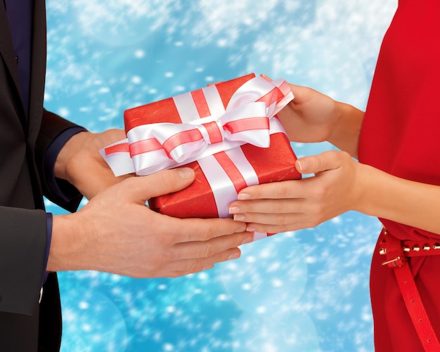 natale, natale, inverno, vacanze, concetto di felicità - mani di uomo e donna con confezione regalo