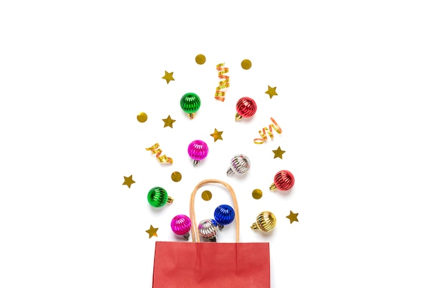 Natale - palline colorate decorazioni albero, luccica sbriciolato dal sacco di carta rosso isolato su sfondo bianco Lay flat