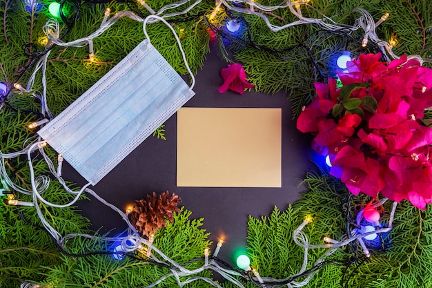 Natale sfondo concetto minimalista. Biglietti di auguri di Natale con decorazioni in foglia di abete, luci, fiori di carta (bouganville) e maschere. Idea. Natale, inverno, piatto, vista dall'alto