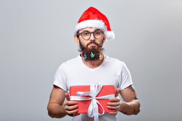 Natale, vacanze, barbiere e concetto di stile - giovane e bello barbuto babbo natale con tante piccole palline di natale in barba lunga.