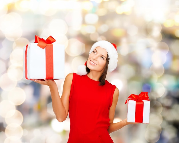 Natale, vacanze, celebrazione e concetto di persone - donna sorridente in abito rosso con confezione regalo su sfondo di luci