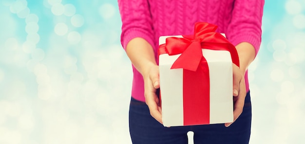 Natale, vacanze e concetto di persone - primo piano di donna in maglione rosa con confezione regalo su sfondo di luci blu