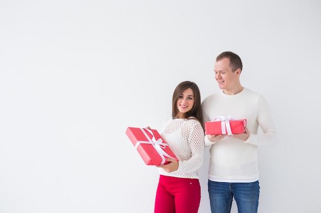 Natale, vacanze, San Valentino e concetto di compleanno - L'uomo e la donna felici tengono scatole con regali su sfondo bianco con spazio per le copie