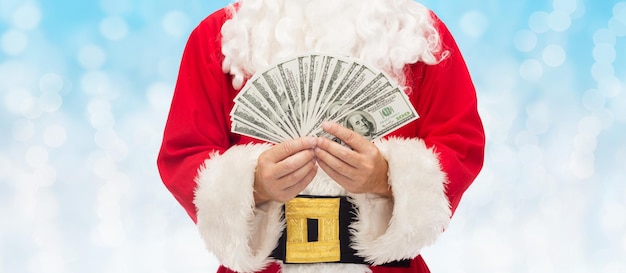 Natale, vacanze, vincita, valuta e concetto di persone - primo piano di Babbo Natale con soldi in dollari su sfondo di luci blu