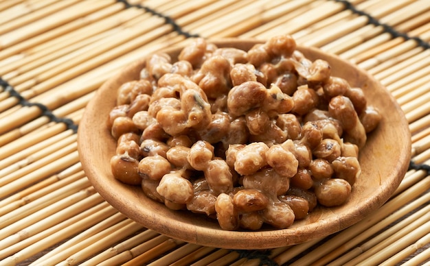 Natto o soia fermentata in piastra di legno su sfondo stuoia di bambù. Natto o soia fermentata