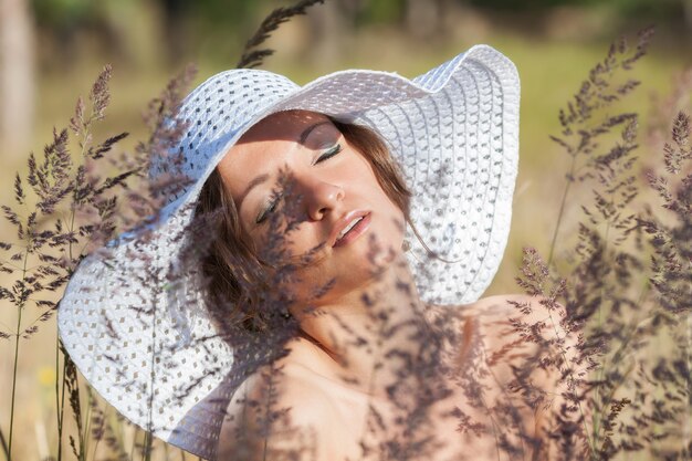 Natura, bellezza, gioventù e concetto di stile di vita sano. Giovane donna in cappello bianco su sfondo di erba naturale. Ragazza all'aperto godersi la natura.