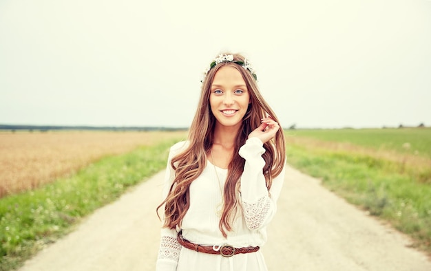 natura, estate, cultura giovanile e concetto di persone - sorridente giovane donna hippie che indossa una corona di fiori sul campo di cereali