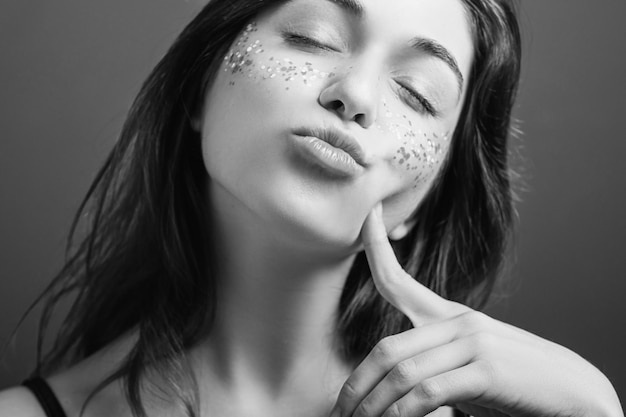 Natura femminile provocante Labbra broncio Dito sulla guancia Occhi chiusi Ritratto narcisista in bianco e nero