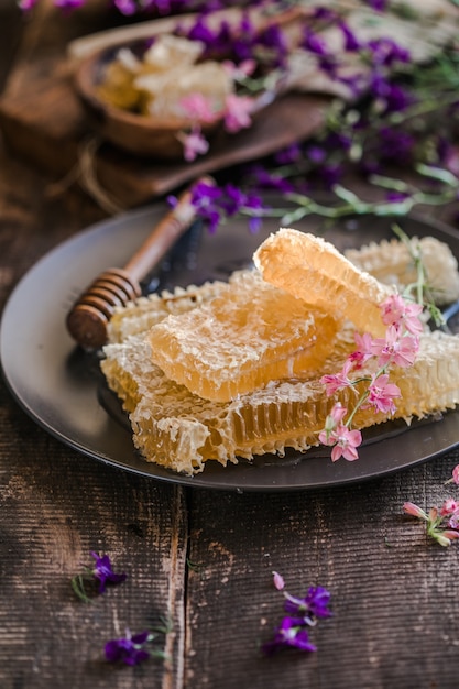 Natura mestolo di miele in legno e favi su sfondo di legno