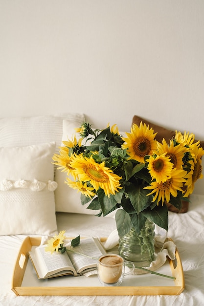 Natura morta all'interno della casa del soggiorno. Girasoli, caffè e libro aperto. Leggi, riposa