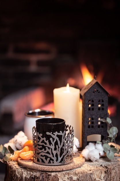 Natura morta con bevande calde, candele e decorazioni con un fuoco ardente. Il concetto di un relax serale vicino al camino.