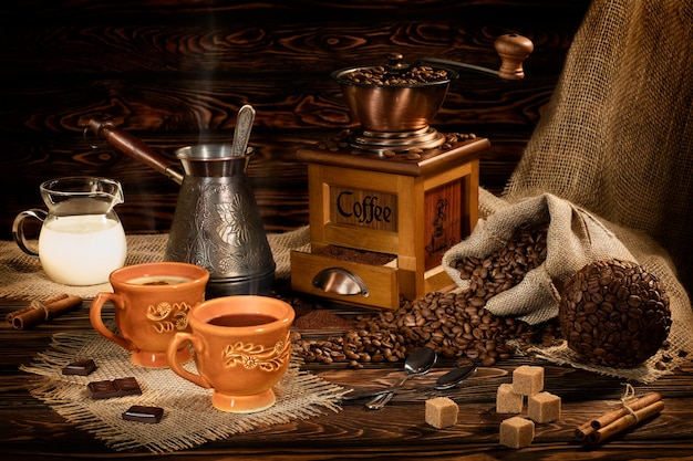Natura morta con chicchi di caffè e vecchio macinacaffè sulla tavola di legno
