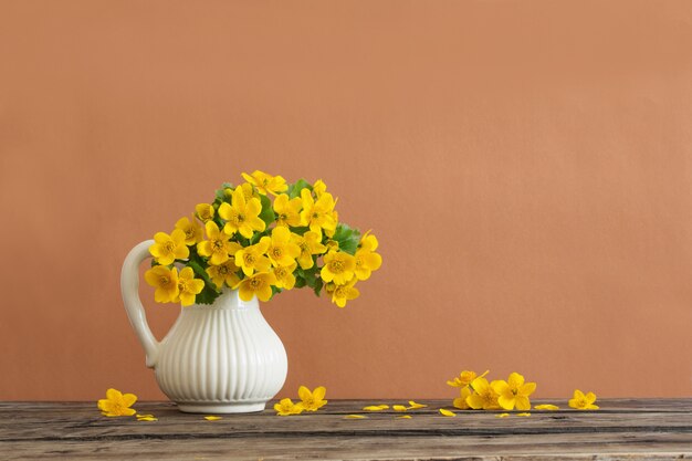 Natura morta con fiori primaverili gialli in brocca