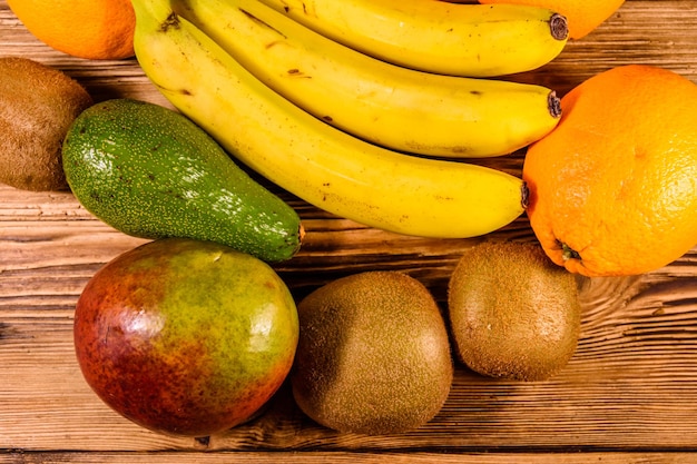 Natura morta con frutti esotici Banane arance mango avocado pompelmo e kiwi su tavola di legno Vista dall'alto