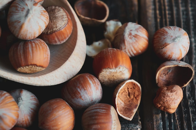 Natura morta con nocciole e nocciole intere su un vecchio tavolo rustico in legno con un cucchiaio e una ciotola di legno con posto per il testo