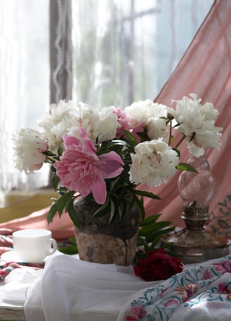 Natura morta con peonie bianche e rosa in un antico vaso di ceramica