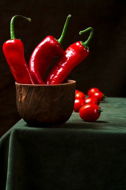 Natura morta con peperoncino in una tazza e pomodori sul tavolo