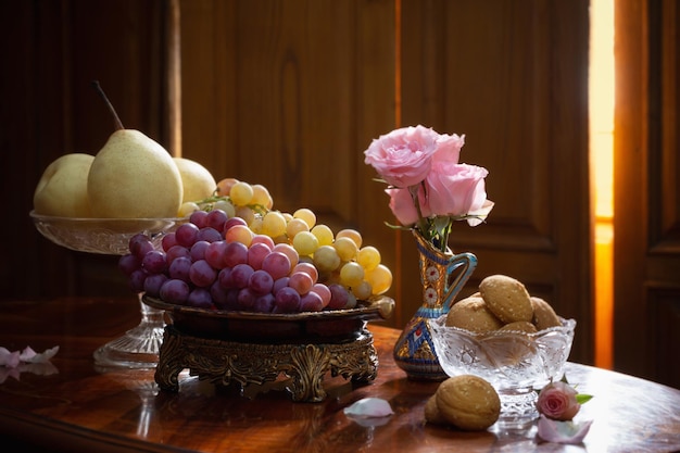 Natura morta con piatti pieni di frutta e fiori in vaso su sfondo di legno