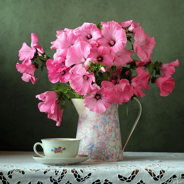 Natura morta con un bouquet nella brocca retrò e tazza sul tavolo