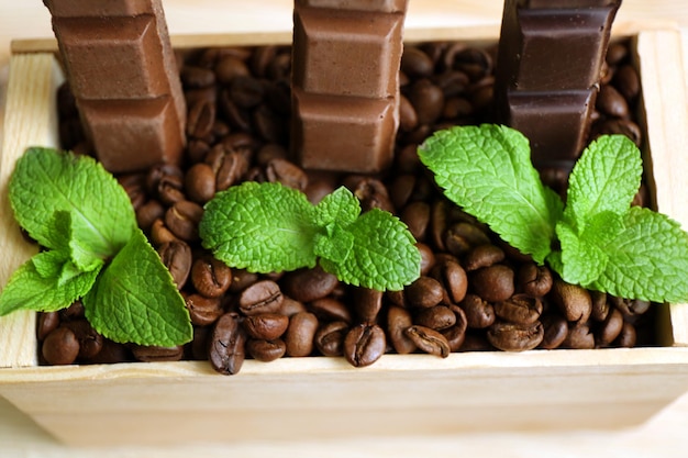 Natura morta con un set di cioccolato in una scatola di legno di chicchi di caffè in primo piano