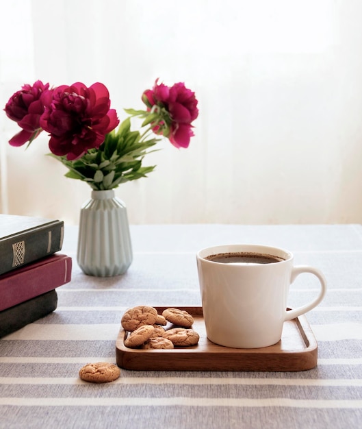 Natura morta con una tazza di caffè e un libro L'atmosfera di una mattina accogliente Colazione a casa o in un bar vicino alla finestra