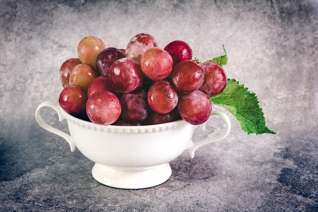 natura morta con uva rossa in tazza vintage bianco