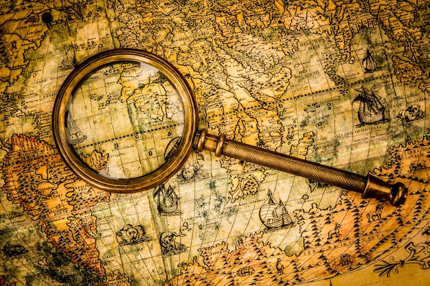 Natura morta d'epoca. La lente d'ingrandimento vintage si trova su un'antica mappa del mondo nel 1565.