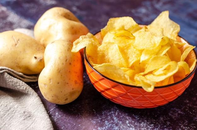 Natura morta di una ciotola di patatine con patate crude e un panno di lino.