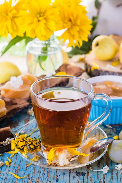 Natura morta estiva con una tazza di tè nero, marmellata di pere e fiori