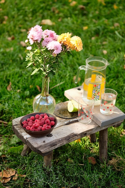 Natura morta estiva: succo di frutta, mela, fiori, lamponi. Bacche, frutti e fiori rustici.