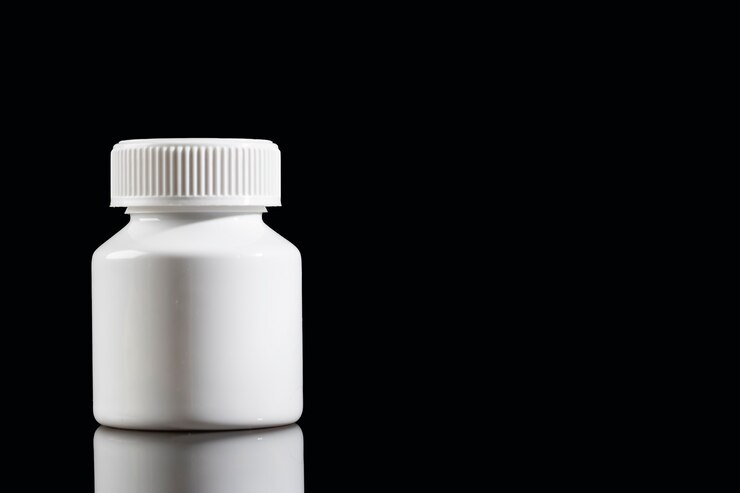 Natura morta medica isolata su fondo nero. Bottiglia bianca di pillole.