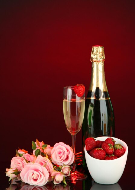Natura morta romantica con champagne, fragole e rose rosa, su sfondo di colore scuro