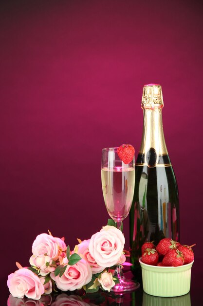 Natura morta romantica con champagne, fragole e rose rosa, su sfondo di colore scuro